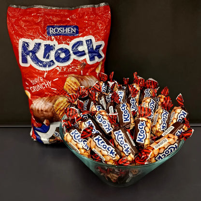 Цукерки Roshen Krock на вагу у скляній мисці поруч з упаковкою