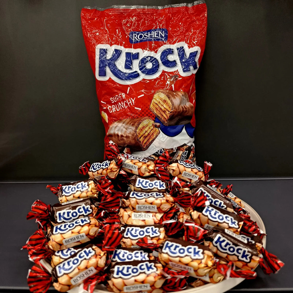 Цукерки Roshen Krock у шоколаді на тлі упаковки Super Crunchy