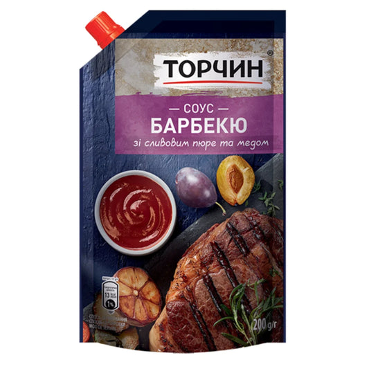 Соус барбекю Торчин 200 г у темно-синьому дой-паку з червоною кришкою, стейком, сливою й мискою соусу